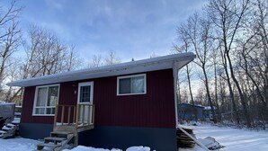 Une petite cabane à un seul étage, dotée d’une terrasse en bois et d’un porche à l’avant.