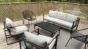 Une terrasse extérieure avec un canapé, des fauteuils et une table.