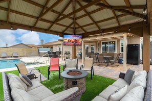 An outdoor patio with a pool, lounge chairs, a fire pit, and a TV screen. - Prime Location HotTub/ Pool/ Outdoor Kitchen Spring training Clean and Safe.  (Glendale)