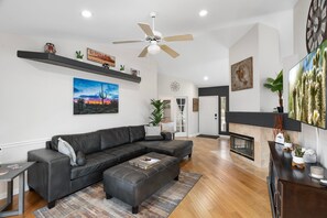 A modern living room with a sectional sofa, a fireplace, and a ceiling fan.
