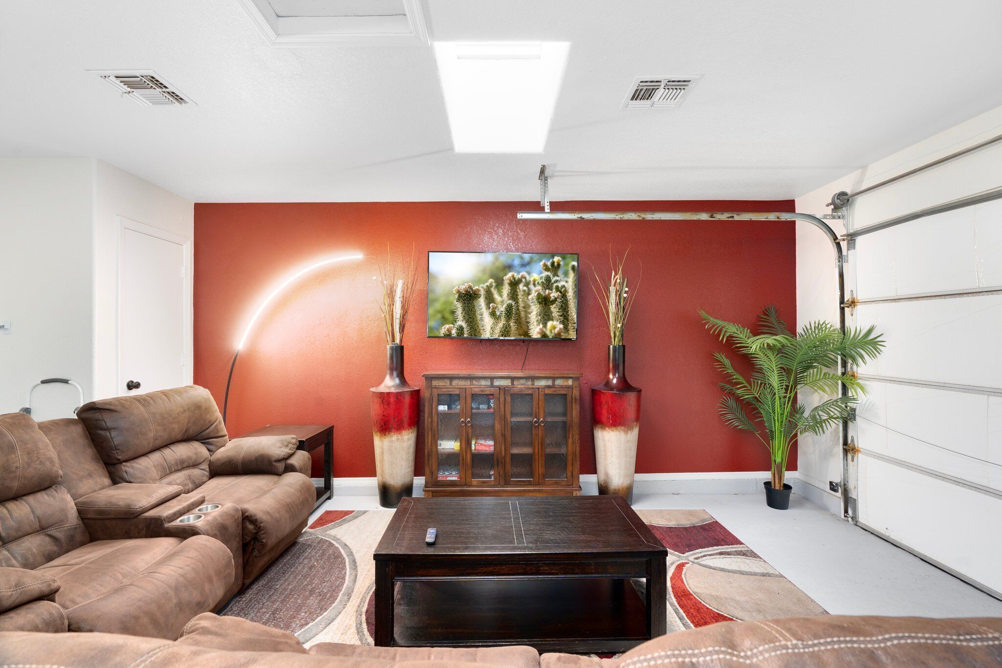 A living room with a brown sofa, a coffee table, a TV mounted on the wall, and a cabinet.