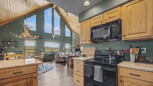 A kitchen with wooden cabinets, a black stove, and a microwave. - Trout Fishing & Panoramic Views - Starlink, 4BR, Pet-Friendly (Fairplay)