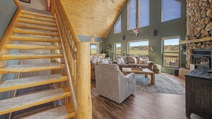 A wooden staircase leading to a loft bedroom with a stone wall and a fireplace. - Trout Fishing & Panoramic Views - Starlink, 4BR, Pet-Friendly (Fairplay)
