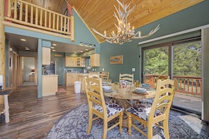 A spacious dining area with a round table, wooden chairs, and a chandelier.
