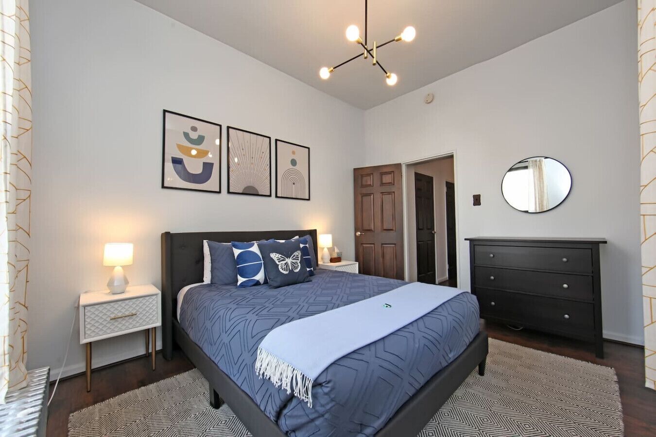 A bedroom with a bed, nightstands, a dresser, and a mirror.