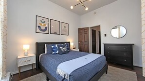 Un dormitorio con cama, mesitas de noche, cómoda y espejo.