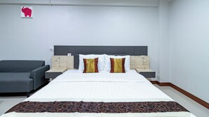 Une chambre d’hôtel avec un grand lit, deux tables de chevet, un canapé gris et une décoration murale représentant un éléphant.