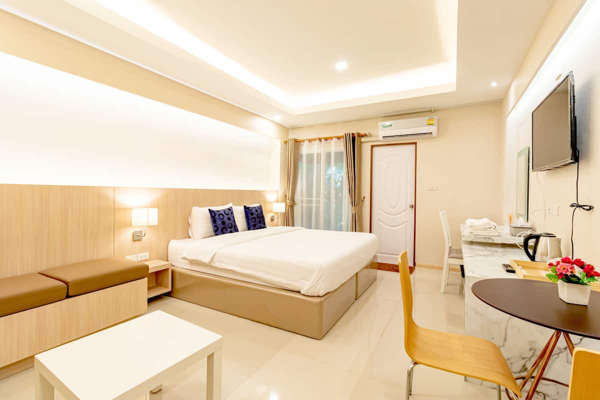 A hotel room with a bed, bedside table, chair, desk, and a small dining area.