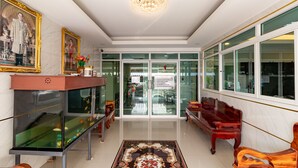 A lobby with a reception desk, a fish tank, a chandelier, and a patterned carpet. - Tree Place by Zuzu (Bangkok)