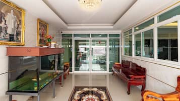 A reception area with a chandelier, a fish tank, a framed portrait, and a red bench.