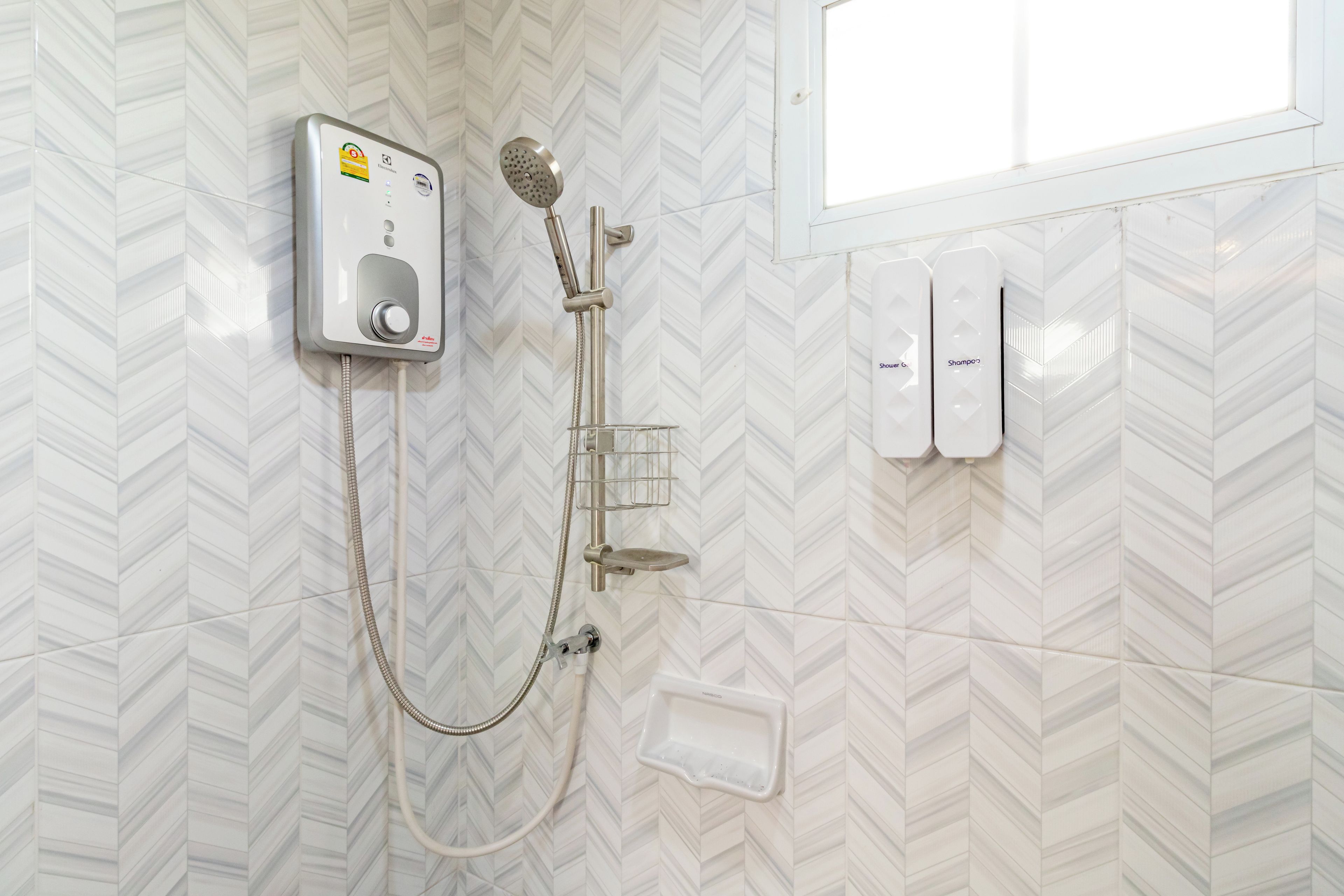 Ducha con cabezal de ducha de mano, panel de control en la pared y dispensador de jabón manual.