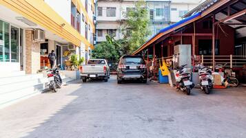 Vista de la calle con vehículos estacionados, edificios y una persona caminando.