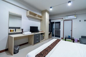 Une chambre d’hôtel moderne équipée d’un lit, d’un bureau, d’une télévision, d’une armoire et d’une salle de bain.