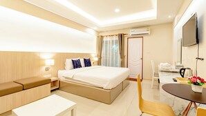 Une chambre d’hôtel comprenant un lit, une table de chevet, une chaise, un bureau et un petit coin repas.