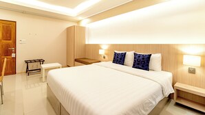 Une chambre d’hôtel moderne avec un grand lit, des tables de chevet, un banc et une armoire.