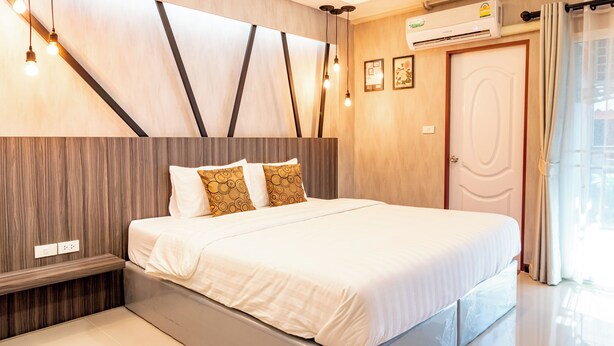 Une chambre moderne avec un grand lit, des murs recouverts de panneaux en bois et un banc intégré.