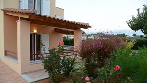 A house with a tiled roof, a wooden pergola, and a garden with pink flowers. - Studio - Apartment for 3 Guests (Nafplio)
