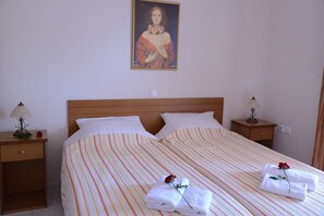 Ein Doppelbett mit gestreifter Bettwäsche, zwei Nachttische mit Lampen und ein Gemälde an der Wand.