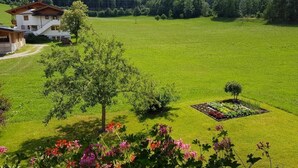A rural landscape with a house, a well-maintained lawn, and a flower bed. - Room-holiday Home Kahr Apartment Roßbran (Radstadt)