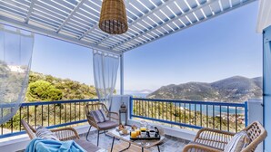 Ein Balkon mit Korbmöbeln, einem Tisch mit Frühstücksgebäck und einem schönen Panoramablick auf die Landschaft.
