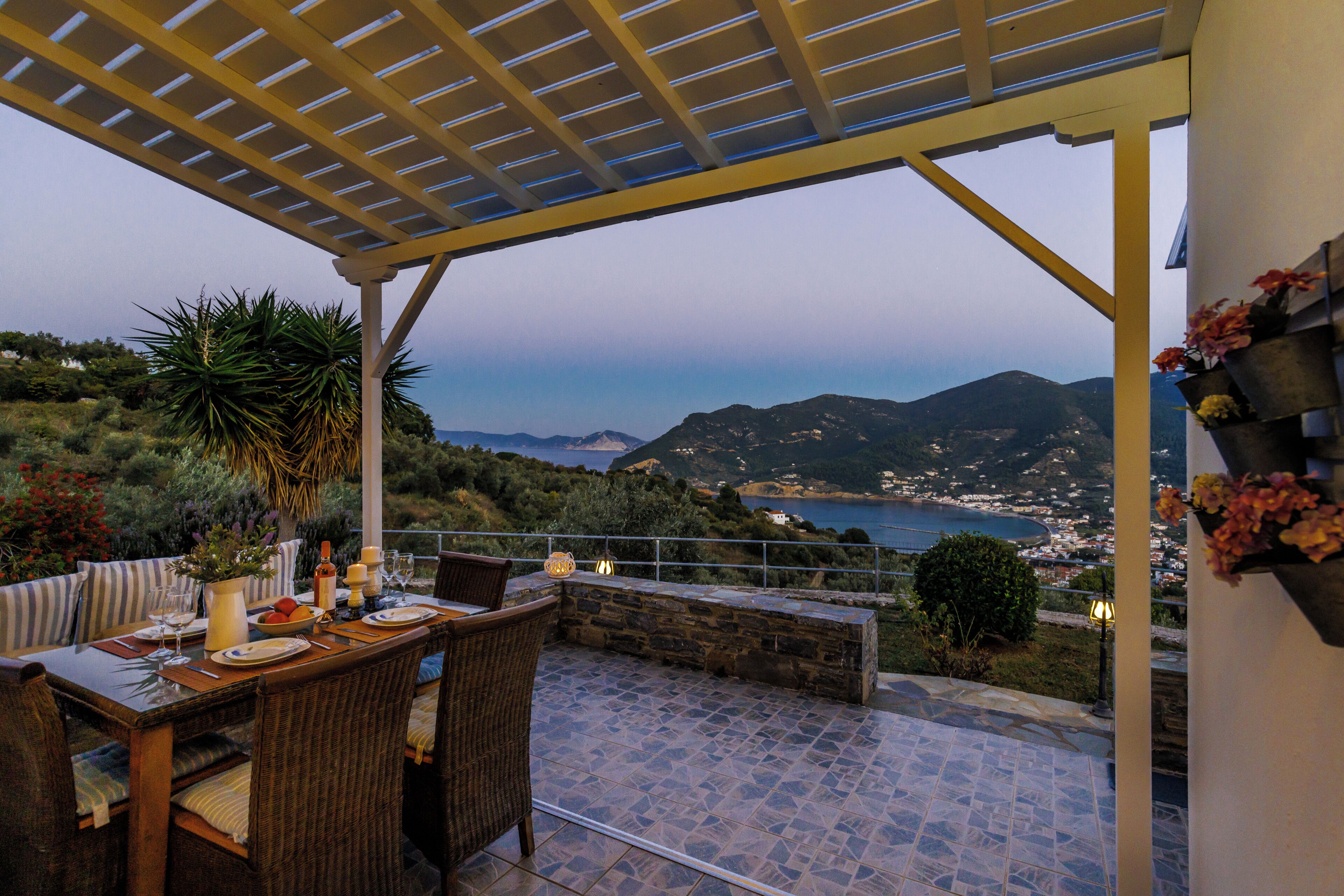 Un espace extérieur aménagé pour prendre les repas, avec vue sur la mer et les collines.