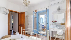 Ein Schlafzimmer mit Bett, Schreibtisch und Stuhl. Eine Tür führt in einen weiteren Raum.