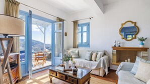Ein Zimmer mit einer Couch, einem Couchtisch, einem Kamin und Blick durch ein großes Fenster.