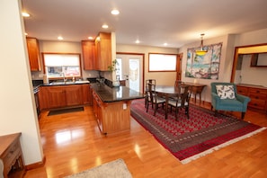 A spacious kitchen with wooden cabinets, a central island, and a dining area with a red patterned rug.