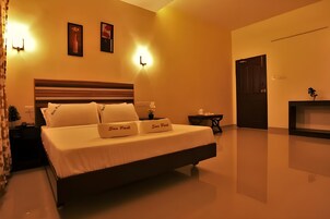 A hotel room with a large bed, two wall-mounted lamps, a small table, and a door.
