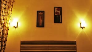 A hotel room with a bed, two wall-mounted lamps, a framed picture, and a curtain.