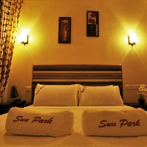A hotel room with a bed, two wall-mounted lamps, a framed picture, and a curtain.