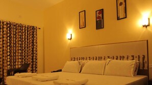 A hotel room with a large bed, a chair, a nightstand, and a wall-mounted light.