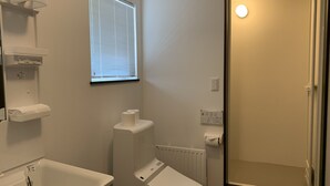 A bathroom with a toilet, sink, and a shower area. - Momiji Brooklyn (Furano)