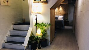 Un escalier menant à une chambre à coucher équipée d’un lit, d’une table de chevet et d’une plante en pot.