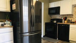 Une cuisine moderne dotée d’appareils électroménagers en acier inoxydable, de meubles blancs et d’un dosseret carrelé.