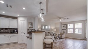 A spacious kitchen with white cabinets, a microwave, and a large island with a bar stool.