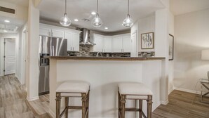 A modern kitchen with white cabinets, stainless steel appliances, and a central island with bar stools.