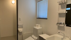 A bathroom with a toilet, sink, and window. - Momiji Montana (Furano)