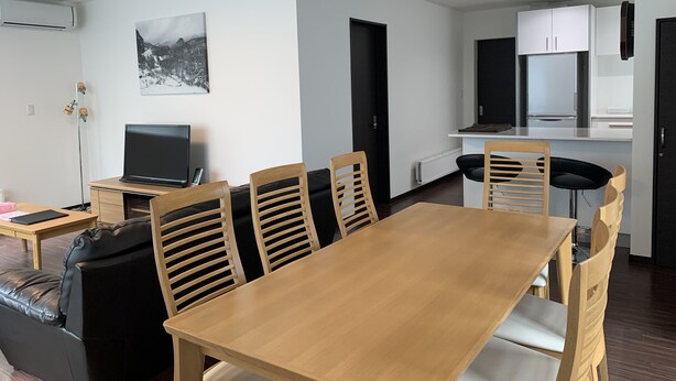 A modern living space with a dining area, a kitchen, and a seating area. - Momiji Montana (Furano)
