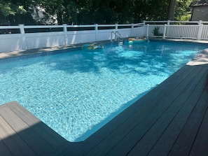 A clear swimming pool with a wooden deck and a white fence in the background. - Bright beach house w/ Private Pool on Trolley loop (Bethany Beach)
