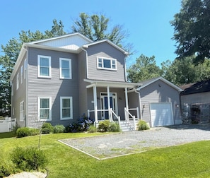 A two-story house with a front porch, a garage, and a well-maintained lawn. - Bright beach house w/ Private Pool on Trolley loop (Bethany Beach)