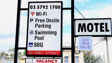 Motel Schild mit Annehmlichkeiten wie WLAN, kostenlosem Parkplatz vor Ort, einem Swimmingpool und Grillmöglichkeiten.