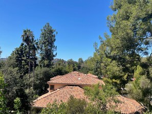 A house with a red-tiled roof, surrounded by dense trees and a clear blue sky. - One bedroom apartment for rent with Kitchen, private entrance and patio. (La Cañada Flintridge)