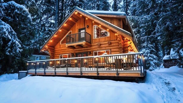 A log cabin with a balcony, surrounded by snow-covered trees. - Stargazer Lodge | Hot Tub + Game Loft (Glacier)
