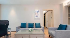 A modern living room with a sofa set, a glass coffee table, and a painting on the wall. - Echarm Hotel Liuzhou Liunan Wanda Plaza (Liuzhou)