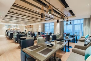 A modern hotel lobby with a central dining area, seating arrangements, and a view of the cityscape. - Echarm Hotel Liuzhou Liunan Wanda Plaza (Liuzhou)