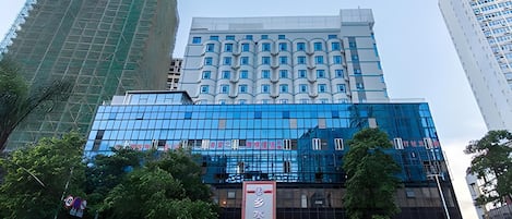 Un hotel de varios pisos con fachada moderna de vidrio, rodeado por otros edificios altos.