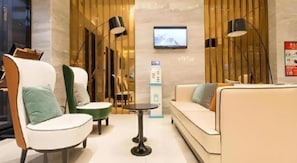 A modern interior with a sofa, chairs, a small table, and a TV mounted on the wall.