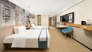 Ein Hotelzimmer mit zwei Betten, einem Fernseher, einem Schreibtisch mit Stuhl und einer großen Wandmalerei.