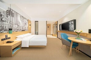 A hotel room with a bed, a desk, a chair, a TV, and a wall with a cityscape mural. - City Comfort Inn Nanning Taoyuan Road (Nanning)